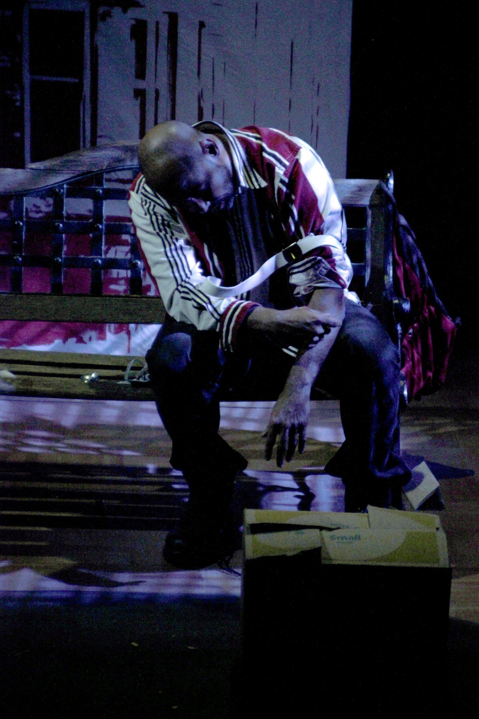 A seated performer under stage lighting in a striped shirt.